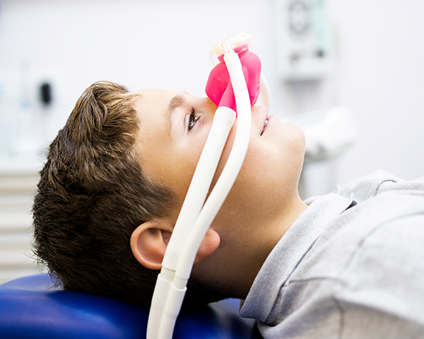Paciente relaxado recebendo tratamento odontológico sob sedação consciente em clínica odontológica.