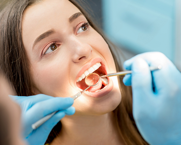 Imagem ilustrativa de um dentista examinando a boca de um paciente em busca de sinais de câncer de boca.