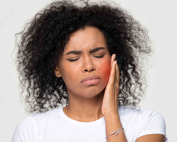 Pessoa com mão na mandíbula expressando dor, representando os sintomas do bruxismo.