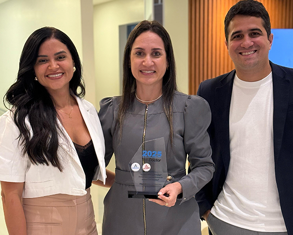 Dra. Simone Abud segurando o troféu da premiação Invisalign Top Doctor Emerald na clínica HOE.