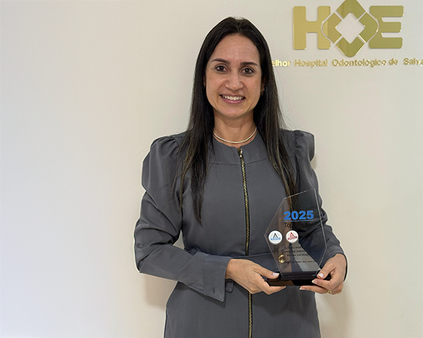 Dra. Simone Abud segurando o troféu da premiação Invisalign Top Doctor Emerald na clínica HOE.