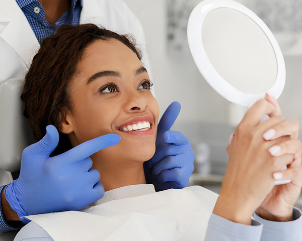 Paciente sorrindo após clareamento dental com dentes visivelmente mais brancos, representando estética e saúde bucal.