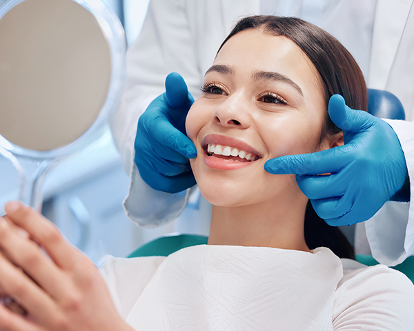Paciente sorrindo após clareamento dental com dentes visivelmente mais brancos, representando estética e saúde bucal.